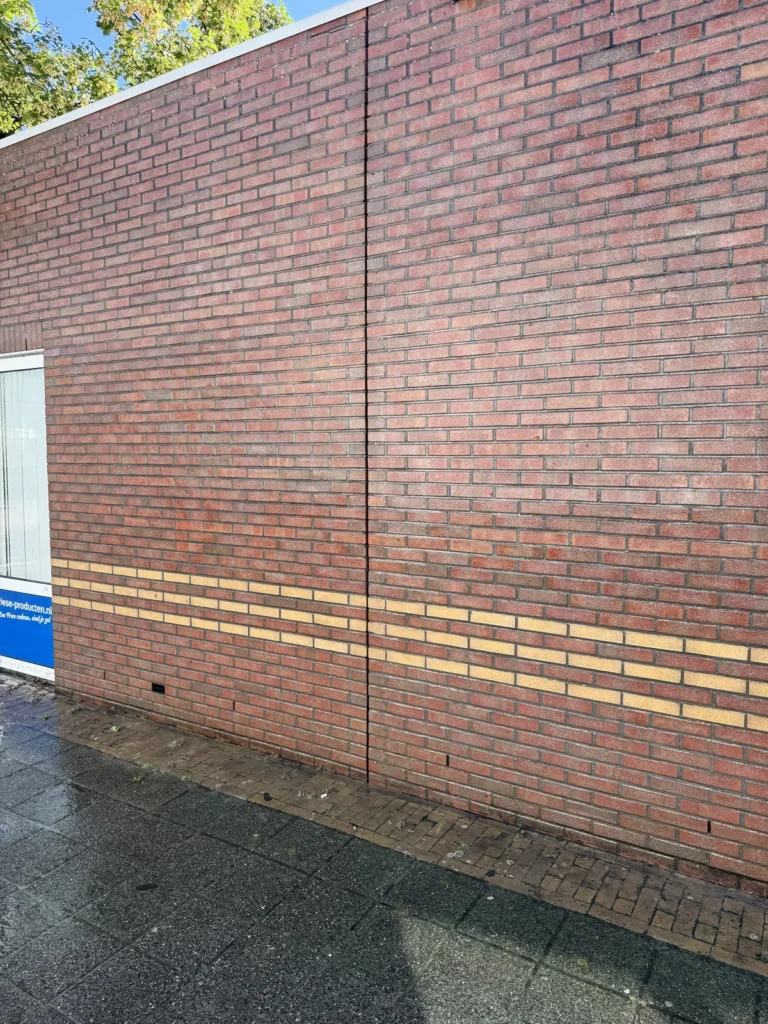 Dezelfde bakstenen gevel na verwijdering van de graffiti