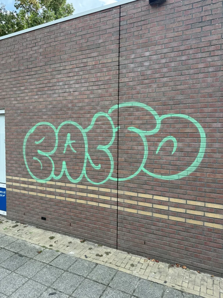 Groene graffiti op een bakstenen gevel voor de reiniging